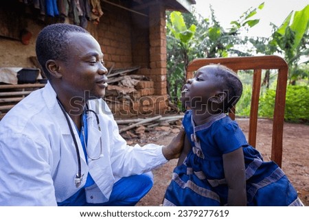 African doctor talking to a sick baby girl during a visit in a rural area in Africa.