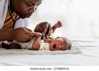 African Doctor Using A Stethoscope, Checking The Respiratory System, Heartbeat Of A 12-day-old Baby Black Skin Newborn, Which Laying And Crying On The Bed, To Baby Black Skin Newborn, Health Concept