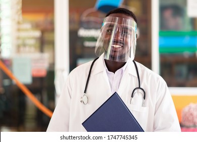 African Doctor Wear Face Shield And Holding Stethoscope With Kind And Smiling