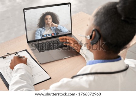 African doctor wear headset consult female black patient make online webcam video call on laptop screen. Telemedicine videoconference remote computer app virtual meeting. Over shoulder videocall view. Stock photo © 