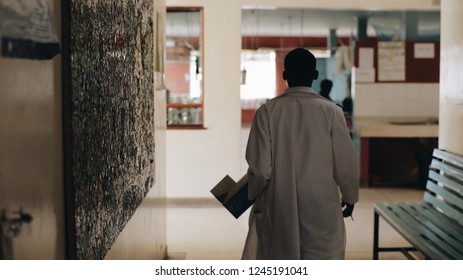 African Doctor In White Medical Gown Walking Through The Hospital Lobby In Village In Africa.