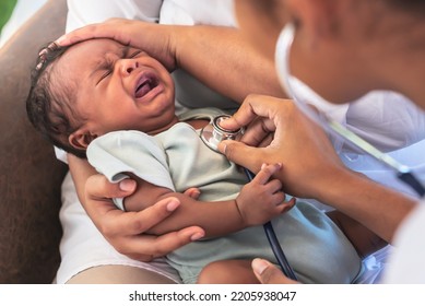 African Doctor Woman Using A Stethoscope, Checking The Respiratory System And Heartbeat Of A 1-month-old Baby Newborn, Who Is Half Nigeria Half Thai, To Infant Health Care Concept.