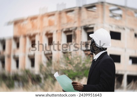 African engineer manager checking blueprint for demolition construction plan and rebuild at the site