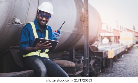 African Engineer Technician Wearing A Helmet, Groves And Safety Vest For Repair The Train With Using Tablet