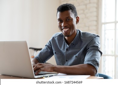 African Ethnicity Office Worker Looking At Camera Smiling While Working At Computer Indoors. Concept Of Leadership, Successful Entrepreneur, Happy Manager, Salesman Broker Or Financial Advisor Concept