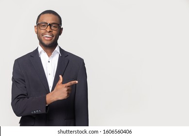 African ethnicity well-dressed businessman wearing formal suit pose isolated on grey studio background, entrepreneur point finger aside at copy space for advertisement text best business offer concept - Powered by Shutterstock