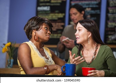 African And European Women In A Coffee House Talking