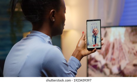 African Famele Having Conference Call With Her Doctor About Illness Treatment Sitting In Living Room Late At Night. Black Patient In A Video Call With Medic Discussing Health Problems Of Woman