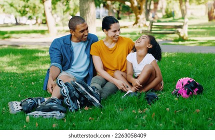African family, girl and park with rollerblades, interracial bonding and laugh for comic joke, happy or holiday. Black man, woman and child with happiness, care and diversity on grass for vacation