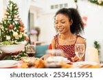 African family having Christmas dinner together at home. People drinking, eating and enjoy talking at dining table. Festive celebration party with delicious feast on holidays.