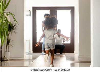 African family having fun in hallway, daughter missed her parents running to mom and dad standing in the doorway of modern house. Family reunion, mortgage happy homeowners arrived a new home concept - Powered by Shutterstock