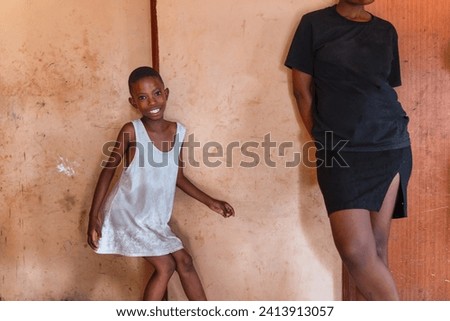 african family in the house , girl dancing next to the wall, unbroken, her sister watching, poverty in the favela