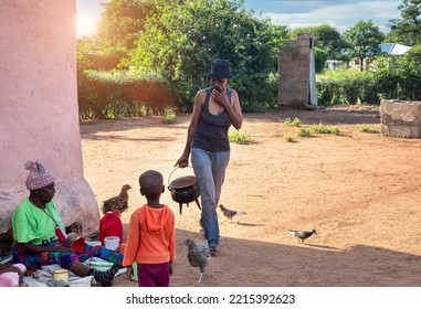 African Family In The Village, Mother Walking And Kids Sited Around Their Grandma In The Yard