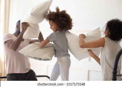 African Family Wearing Home Or Night Clothes Having Fun In The Morning With Little Kid, Parents Fighting Pillows With Lovely Cute Daughter, Pleasant Active Spending Pastime, Leisure Activity Concept