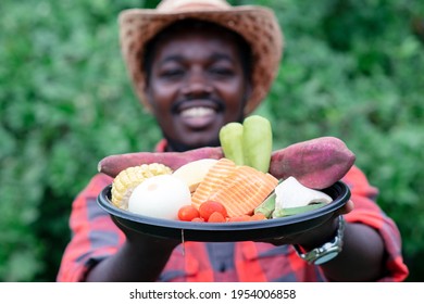 African farmer holding package of vegetables. Organic vegetables ready to serve in salad delivery service - Powered by Shutterstock