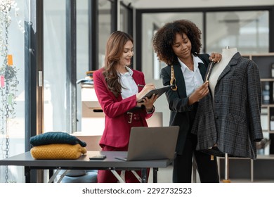 African fashion designer or dressmaker Americans and Asians brainstorm and discuss the design of the new collection with fabric samples and laptop sketches. work together in the studio. - Powered by Shutterstock