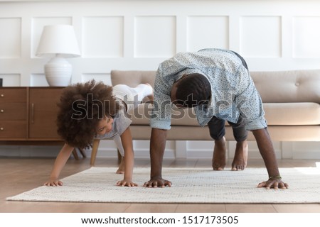 African father and small daughter in casual clothes do pushup pressup exercise on carpet on warm floor in living room, sporty lifestyle, getting physically stronger, have fun, pastime with kid concept