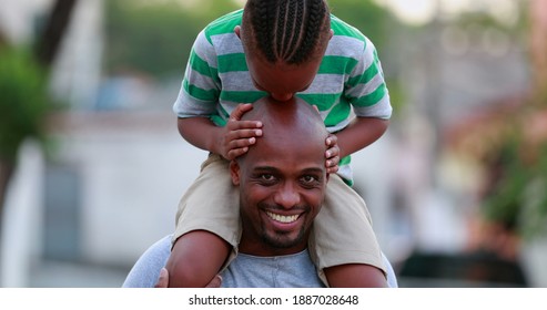 African Father And Son Bonding. Kid Kissing Dad Bald Head, Child On Top Of Father Shoulders