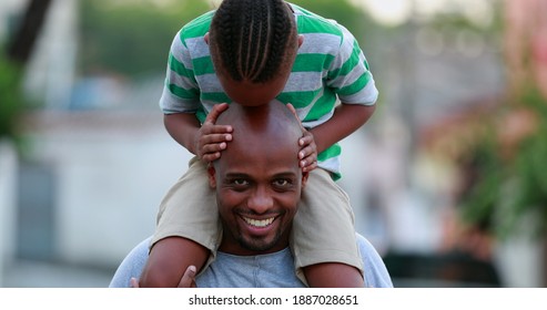 African Father And Son Bonding. Kid Kissing Dad Bald Head, Child On Top Of Father Shoulders