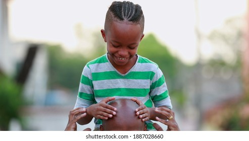 African Father And Son Bonding. Kid Kissing Dad Bald Head, Child On Top Of Father Shoulders