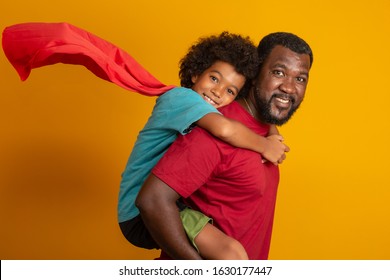 African Father and Son playing Superhero at the day time. People having fun yellow background. Concept of friendly family. - Powered by Shutterstock