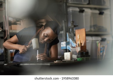 African Female Artisan Working On Leather With A Mallet And Punch