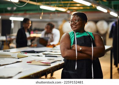 african female business woman textile industry wearing a green shirt with black apron measuring tape with arms folded