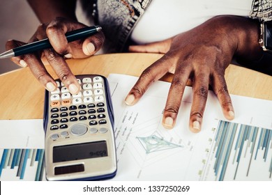 African Female Businessmen Are Analyzing Financial Graphs Using Calculators To Compare Data For Accuracy.

