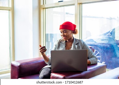 African female businesswoman shopping for home using laptop computer holding credit card