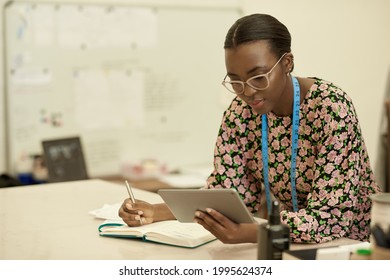 African female clothes designer working on a tablet in her studio