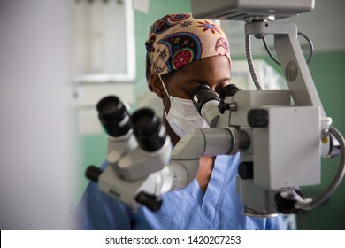 African Female doctor looking through Operating microscope equipment with face mask Cape Town South Africa. 