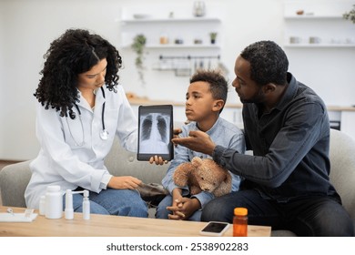 African female doctor presents lungs x-ray on tablet to young boy and his worried father. Scene takes place in modern living room, creating supportive atmosphere. - Powered by Shutterstock