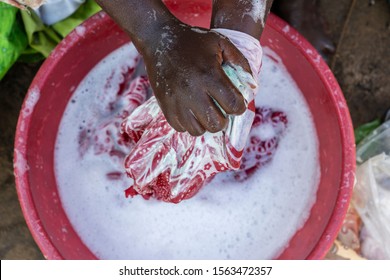 African Female Hands Washing Clothes In Basin On A Street Near Home Of Zanzibar Island, Tanzania, East Africa . Wash Stain Of Dirty Clothing By Hand With Detergent. Close Up