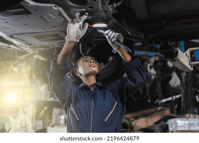 African Female Mechanic Fixing Underneath Car In Auto Repair Service, Black Woman Vehicle Technician Checking Car Problem And Changing Spare Parts In Garage 