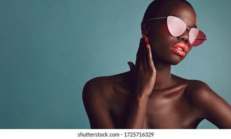 African Female Model Wearing Funky Sunglasses. Looking Away. Stylish Woman With Buzzcut On Grey Background.