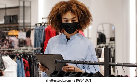 African Female Shop Manager Worker Girl Seller Clothing Store Administrator Make Inventory Salesperson Woman In Medical Face Mask Owner Boutique Writing Information About Product Discount Size Price
