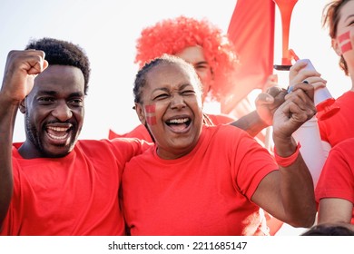 African football fans celebrating and supporting their team at sport stadium - Focus on senior woman face. - Powered by Shutterstock