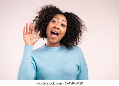 African friendly woman waving hand - hello. Greeting, say Hi to camera. Beautiful young girl on beige studio background - Shutterstock ID 1945843420