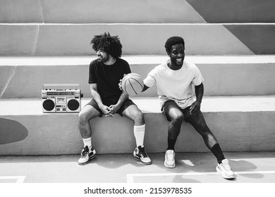 African friends listening music from vintage boombox stereo outdoor after basketball match - Focus on man with curly afro hair - Black and white editing
