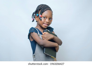 African girl child happily hugging and embracing educational books indoor as she believes education increases intelligence and knowledge which can be gotten from studying, reading, and learning 