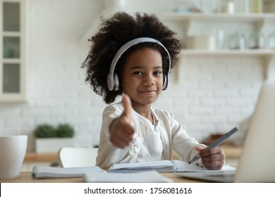 African girl in headphones enjoy e-learn sit at table showing thumbs up recommend e-study easy and interesting app for children, using modern tech. Homeschooling, clever kid and self-education concept - Powered by Shutterstock