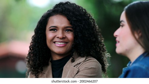 African Girl Listening To Friend In Conversation Outside, Diverse Female Friends Talk At Park