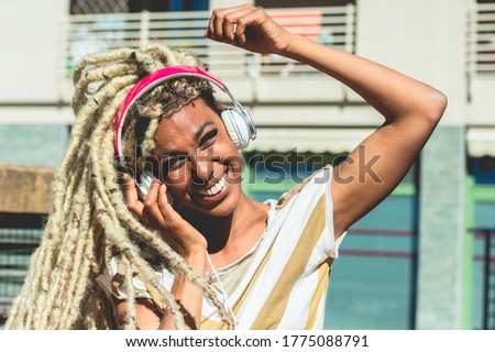 African girl moving blond dreadlocks hair wearing while listening music playlist with headphones - Youth lifestyle and trendy people concept - Focus on face