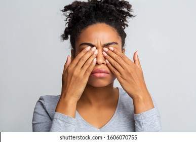 African girl rubs her eyes, suffering from conjunctivitis, ocular diseases concept