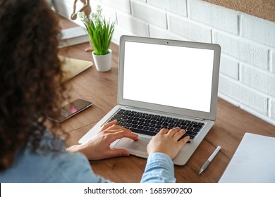 Африканская школьница, обучающаяся на дистанционном учебном курсе, учится в домашнем офисе. Этническая молодая женщина смотрит онлайн-образовательный вебинар с помощью ноутбука. Через плечо крупным планом макет экрана