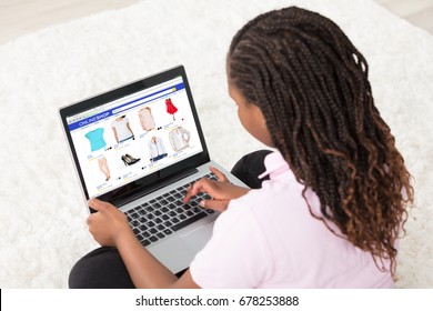 African Girl Sitting On White Carpet Doing Online Shopping Using Laptop At Home