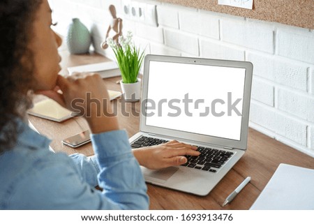 African girl student watching video course, distance e-learning, studying with online teacher by webcam. Remote education, work from home concept. Over shoulder close up laptop mock up screen view.