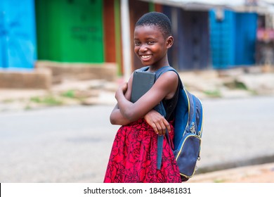 An African Girl Student Wearing Bag Pack And Holding Digital Tablet-smiling And Looking At Camera