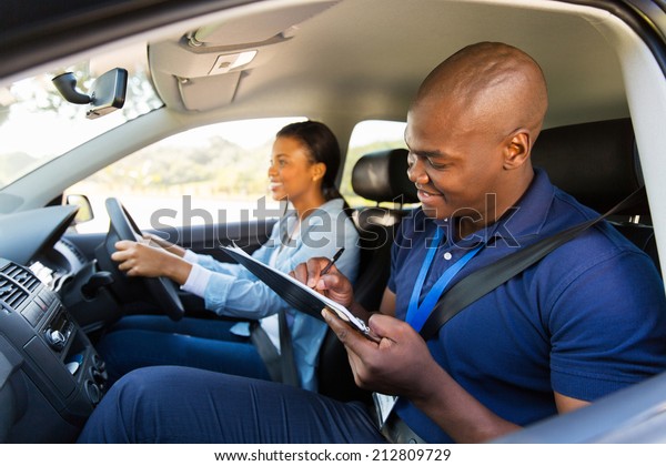 african girl taking driving test with\
professional instructor