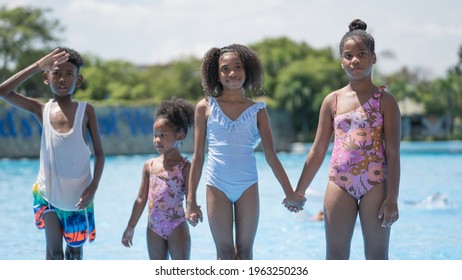 African girls and boy standing and playing in swimming water pool at amusement park.  Concept kid are expressing pure joy and excitement